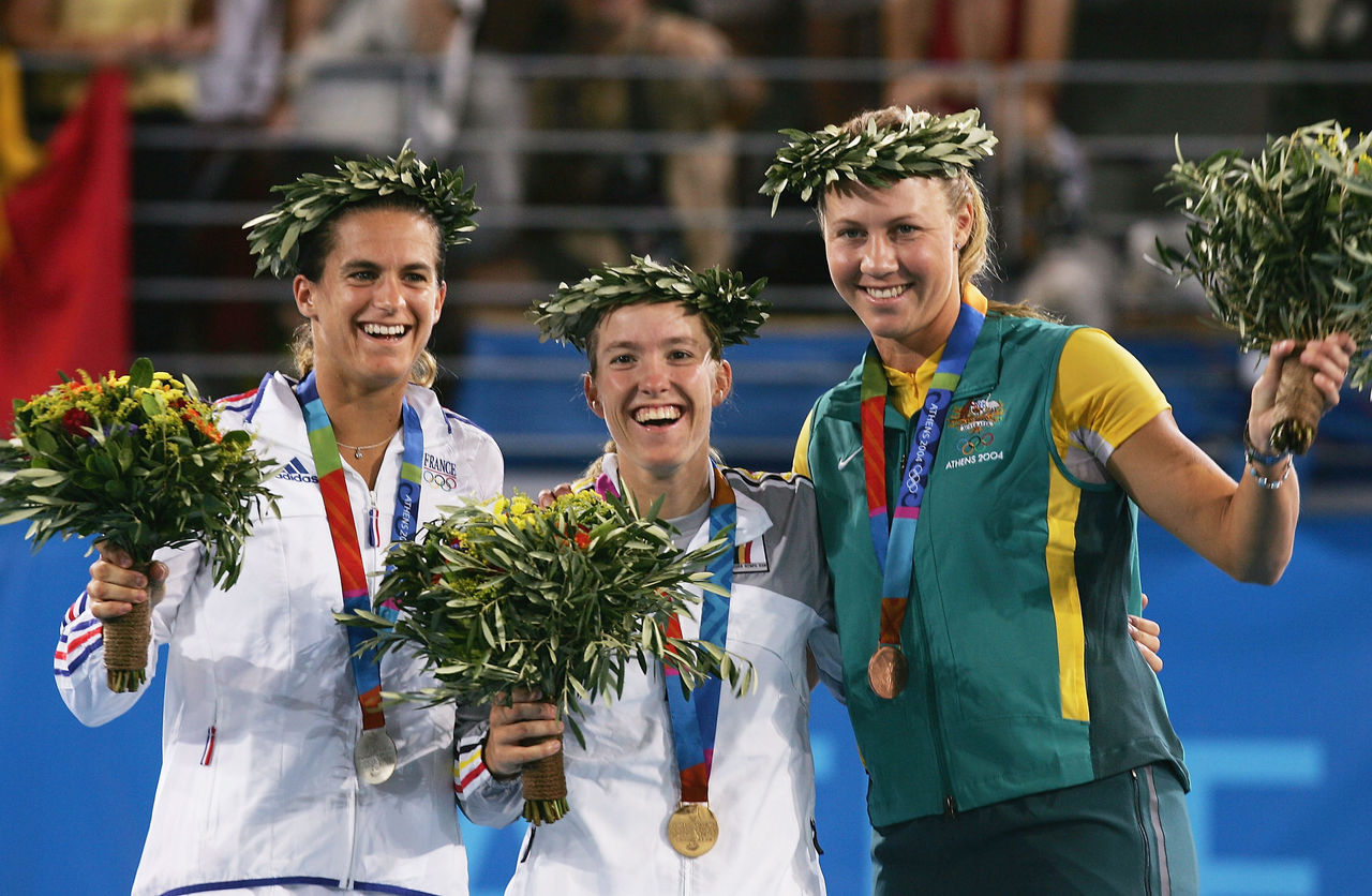 ATHENS - AUGUST 21:  (L-R)  Amelie Mauresmo of France (silver), Justine Henin-Hardenne of Belgium (gold) and Alicia Molik of Australia (bronze) wave to the crowd during the medal ceremony for the women's singles tennis event on August 21, 2004 during the Athens 2004 Summer Olympic Games at the Olympic Sports Complex Tennis Centre in Athens, Greece. (Photo by Clive Brunskill/Getty Images)
